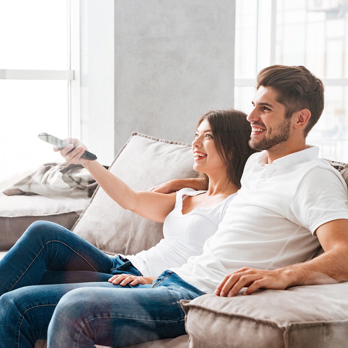 joyful-couple-enjoying-television-at-home-SBI-302823658